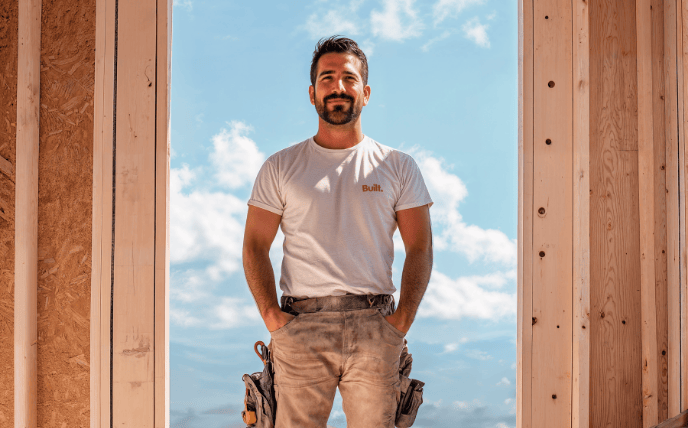 A smiling builder stands on a construction site