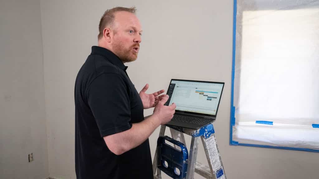 Customer discusses Buildxact with his laptop perched on a ladder