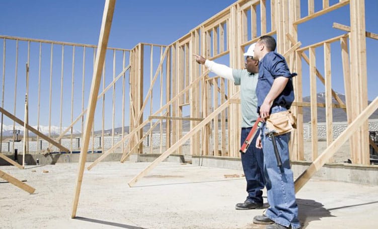 home builders evaluate the framing of a house under construction.