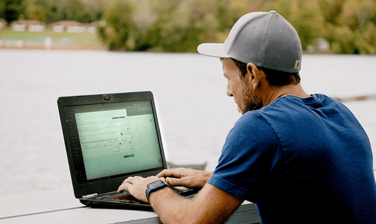 Residential builder reviewing job details on a laptop at the site, capturing scope and cost decisions while work is still underway.
