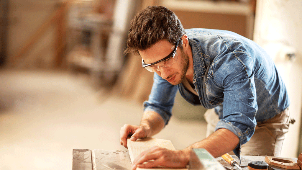 A carpenter adjusts a piece of lumber before cutting