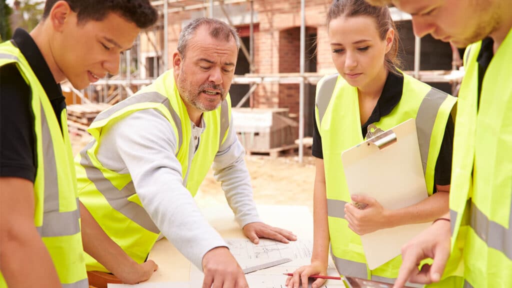 A group of building professionals discussing job safety on a construction site.